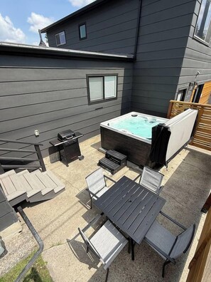 A backyard with a hot tub, a barbecue grill, and outdoor furniture. - Luxury Livingston Retreat + Hot Tub (Livingston)