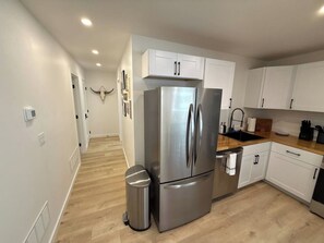 A modern kitchen with white cabinets, a stainless steel refrigerator, and a wooden countertop. - Luxury Livingston Retreat + Hot Tub (Livingston)