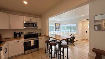 A modern kitchen with a central island, bar stools, and a dining area with a sofa.