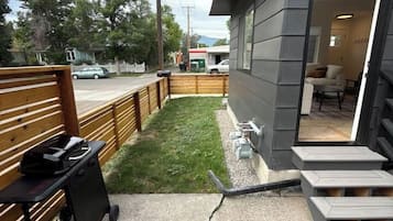 A residential property with a concrete driveway, a wooden fence, and a small lawn area.