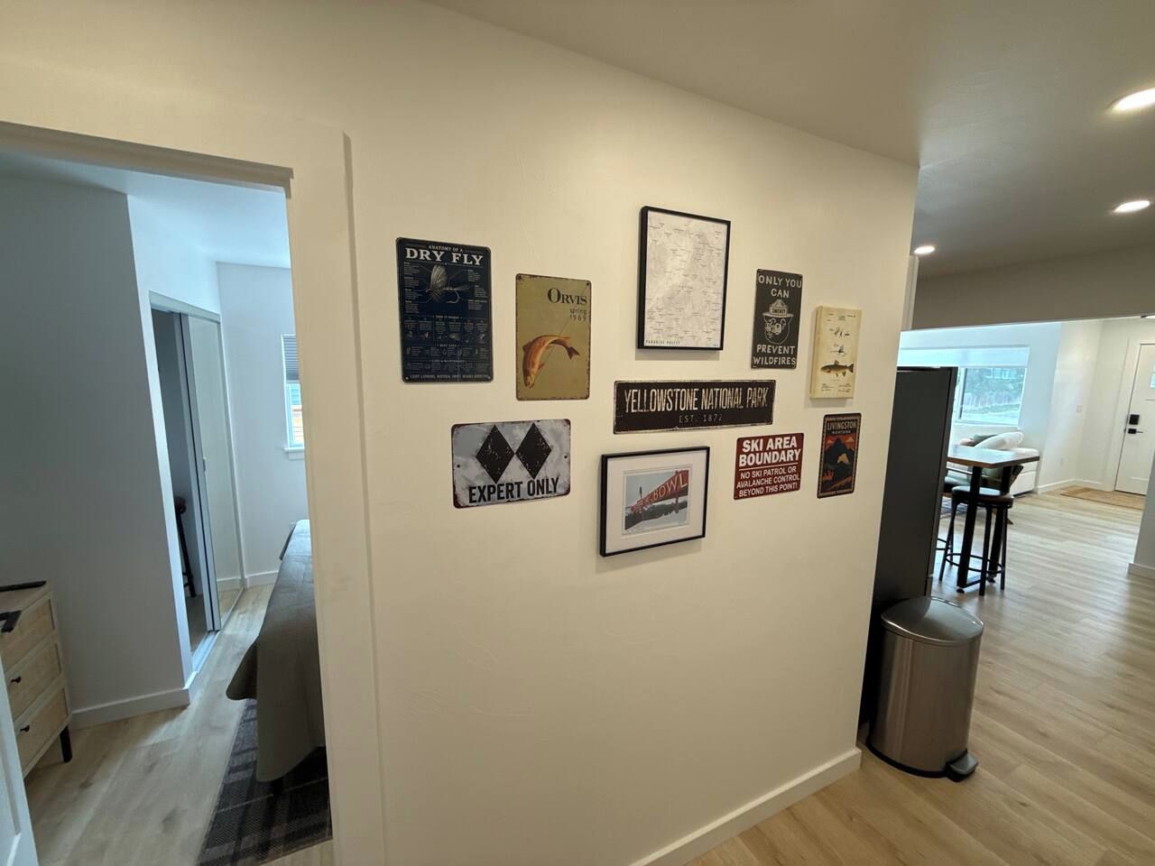 A hallway with a wall decorated with various signs and a framed picture.