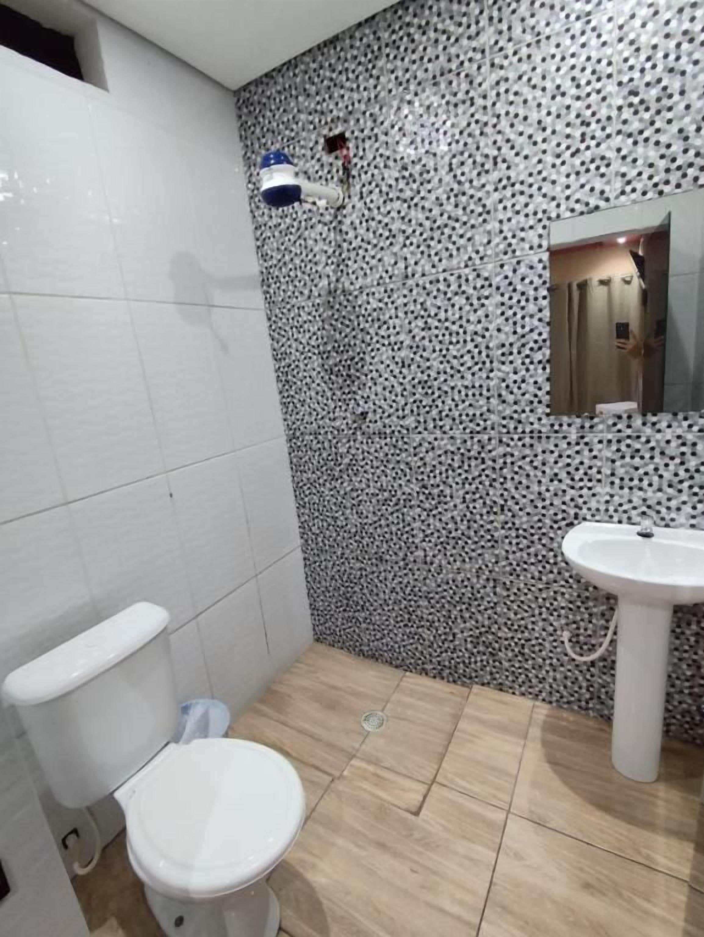 Ein Badezimmer mit Toilette, Waschbecken und einer Wand mit Muster.