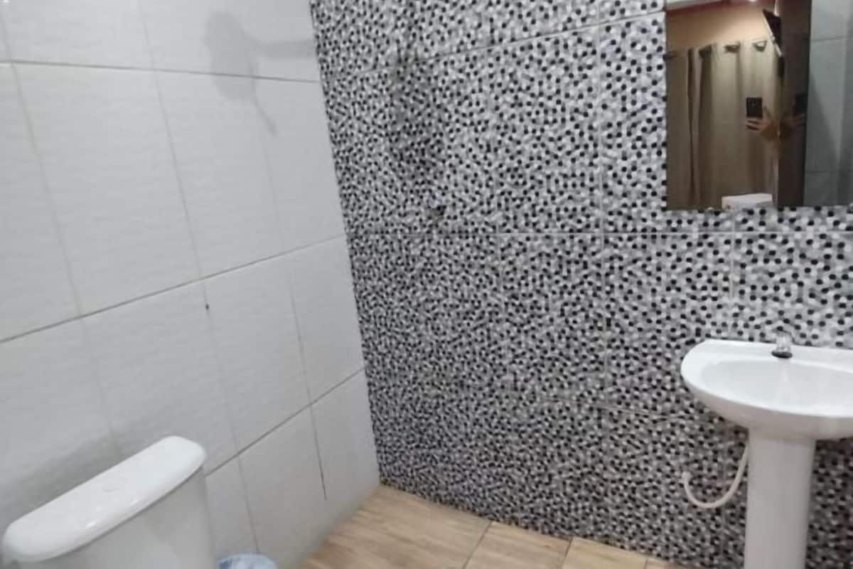Un baño con inodoro, lavamanos y pared con diseño.