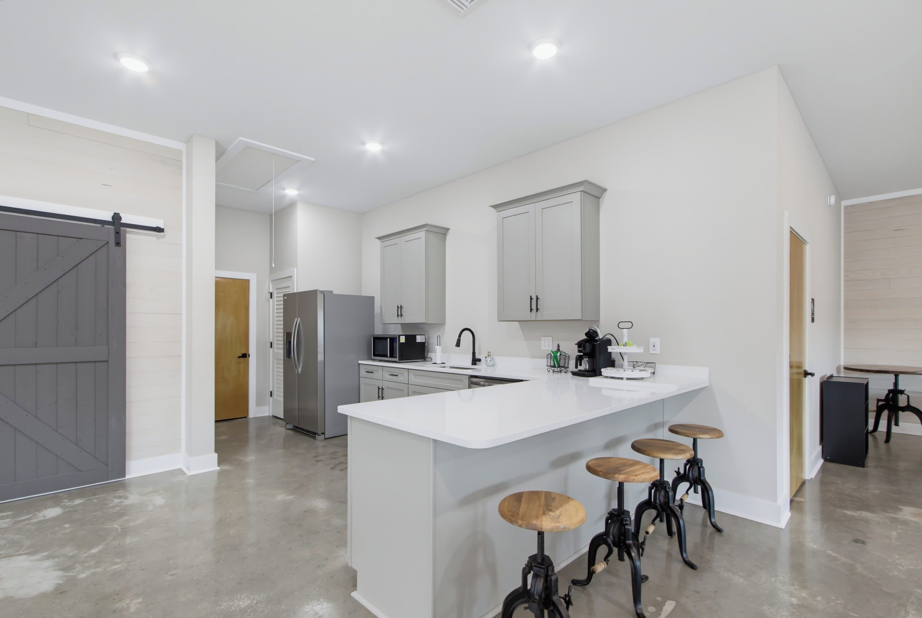 A modern kitchen with a central island, bar stools, and a refrigerator.