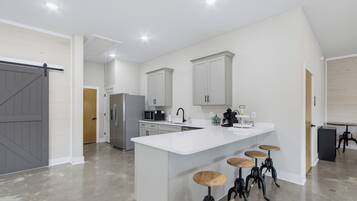 A modern kitchen with a central island, bar stools, and a refrigerator.