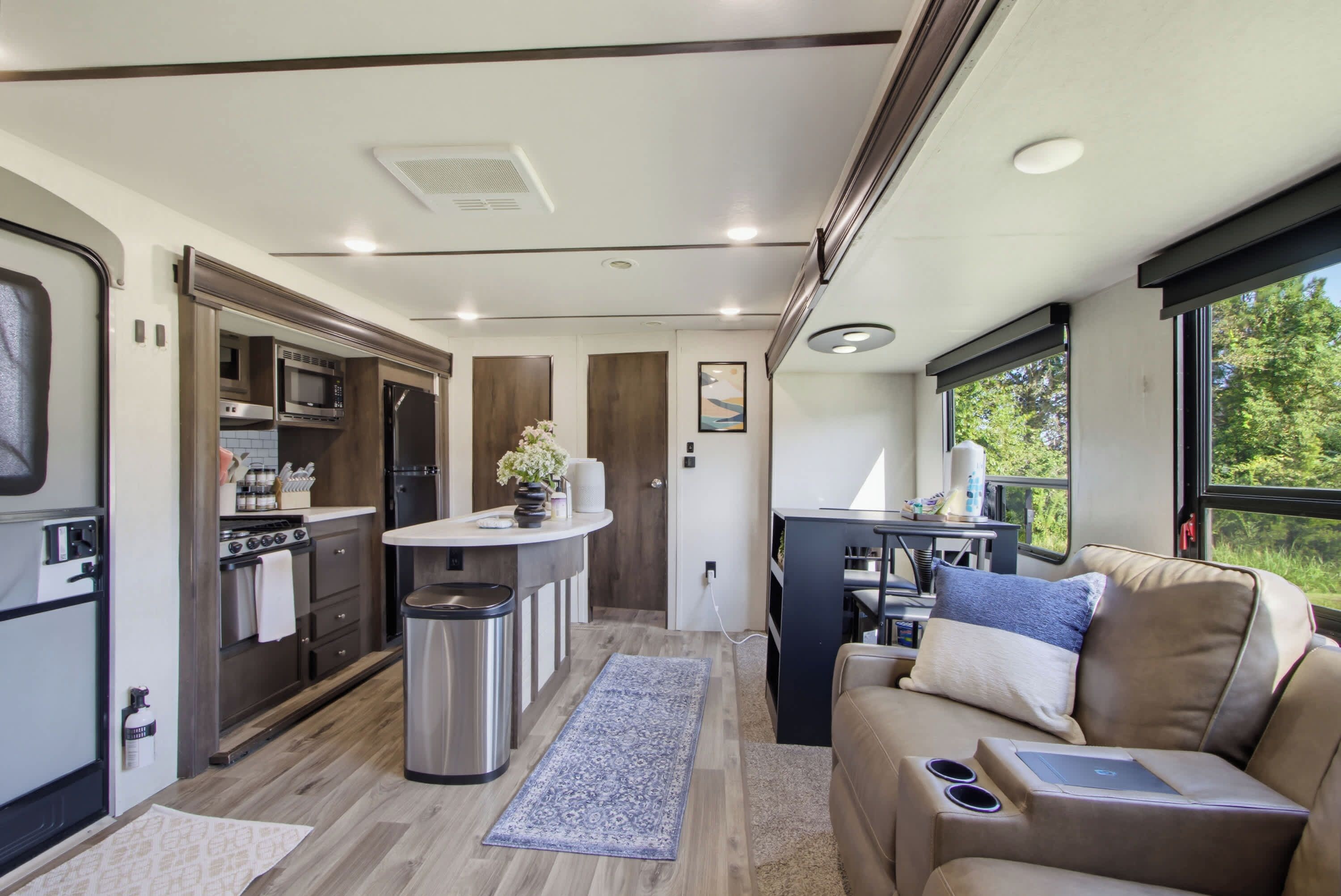 Un intérieur de camping-car compact comprenant un coin cuisine, un espace repas et un coin salon avec vue.