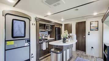 A compact kitchenette with a stove, microwave, and refrigerator.