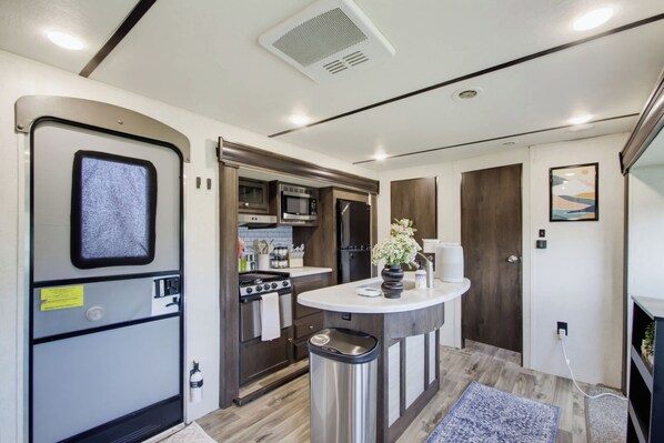Una kitchenette compacta con estufa, microondas y refrigerador.