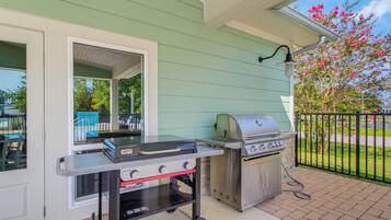 An outdoor grill station with a Weber brand grill, a portable gas stove, and a grill cart.