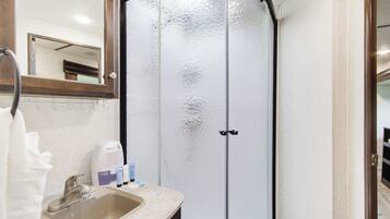 A bathroom with a shower, a sink, and a mirror.