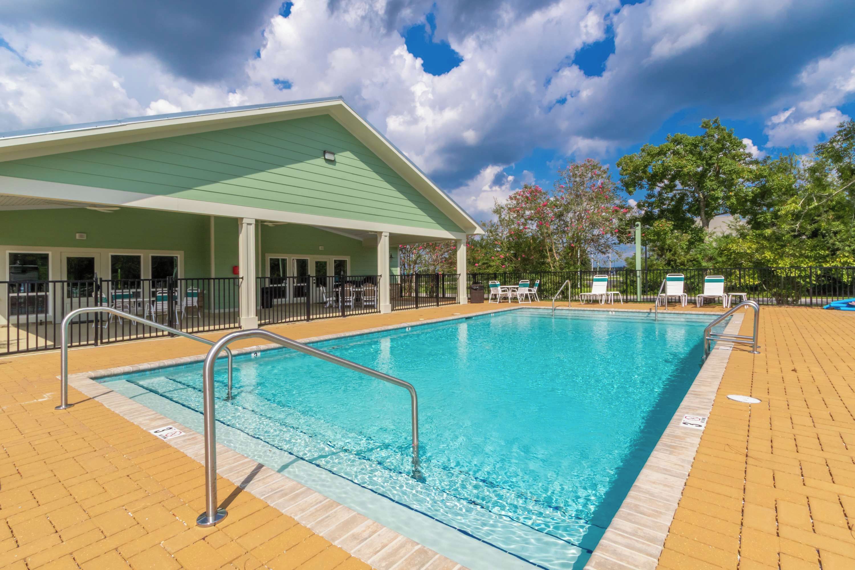 A swimming pool with a covered area, lounge chairs, and a fenced deck.