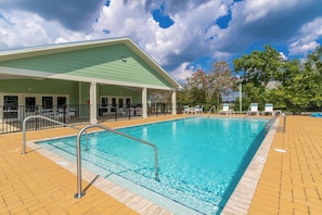 A swimming pool with a covered area, lounge chairs, and a fenced deck.