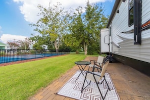 A patio with a table and chairs, a pool, and a white RV.