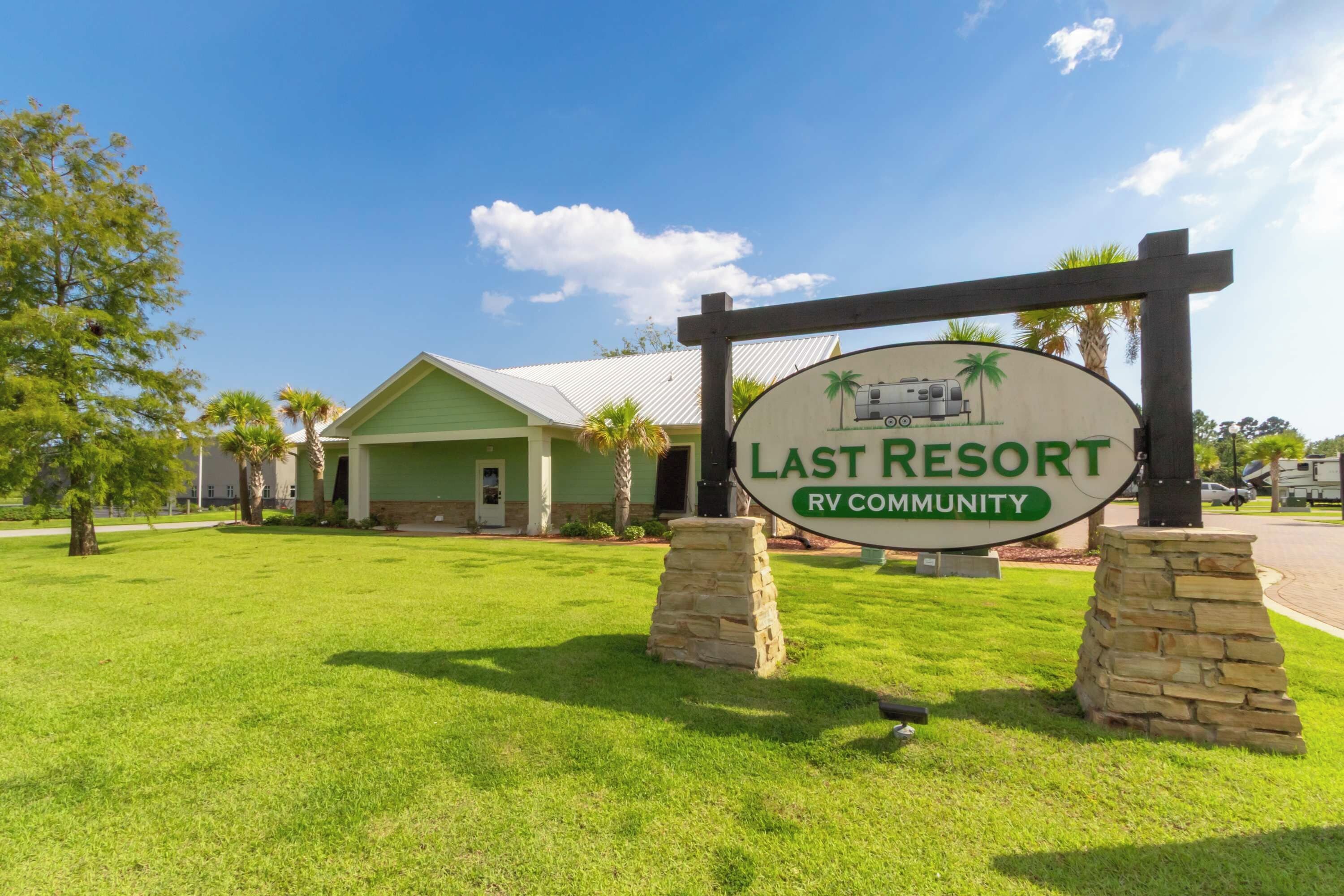 A sign for Last Resort RV Community with a green building in the background.