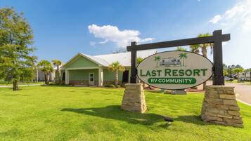 A sign for Last Resort RV Community with a green building in the background.