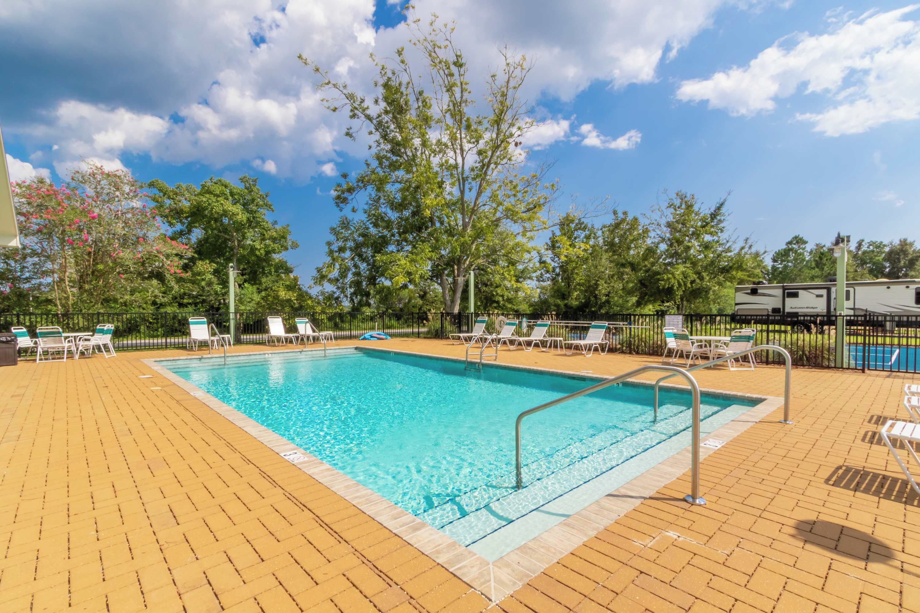 A rectangular swimming pool with clear blue water, surrounded by a brick deck.