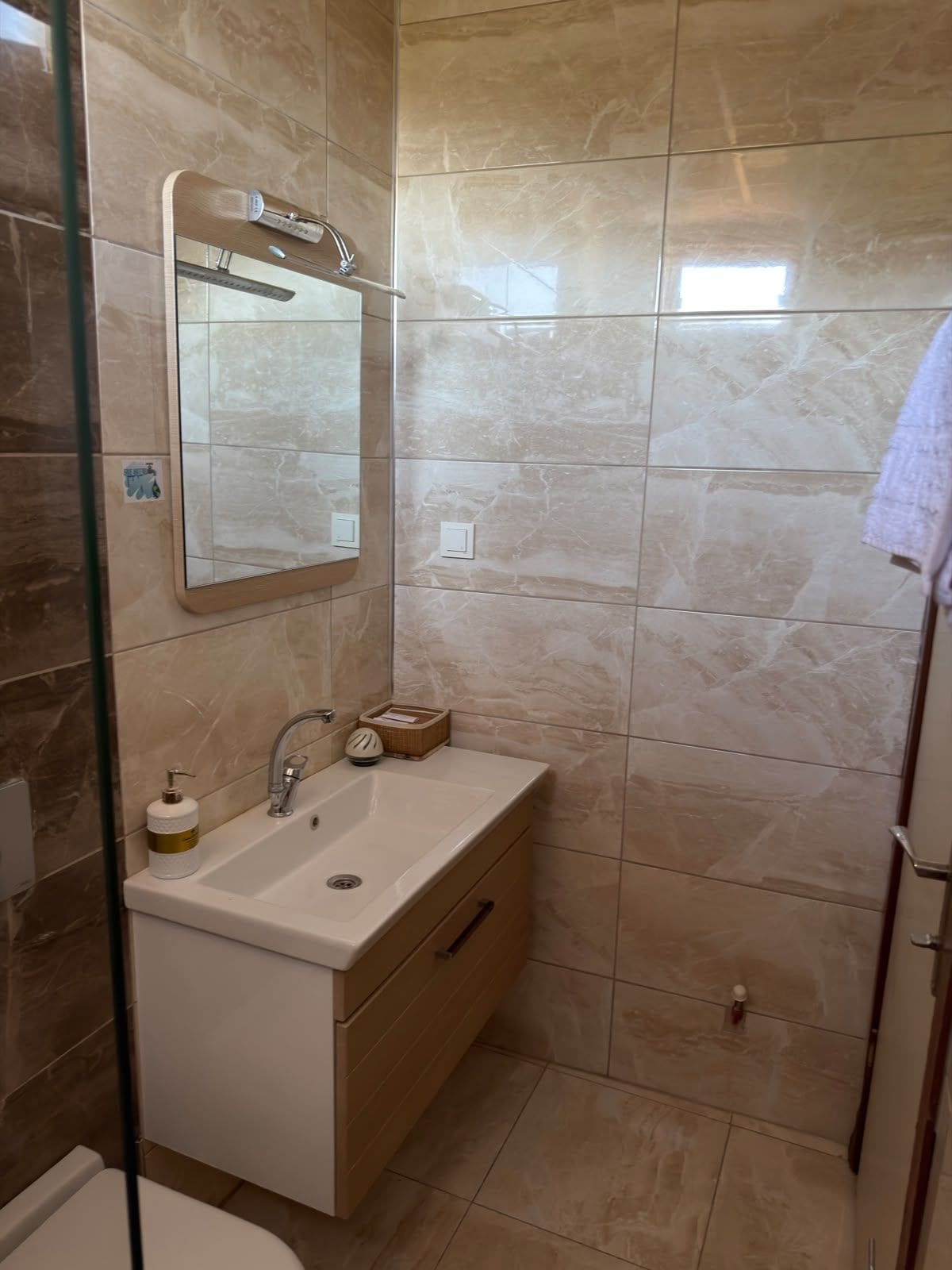 A bathroom with a mirror, sink, and a towel rack.