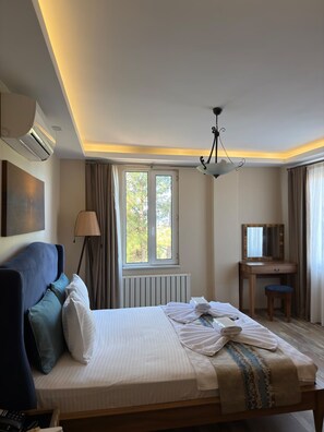 Una habitación de hotel con cama, escritorio, silla, ventana y lámpara en el techo.