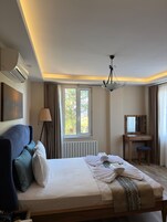 Una habitación de hotel con cama, escritorio, silla, ventana y lámpara en el techo.