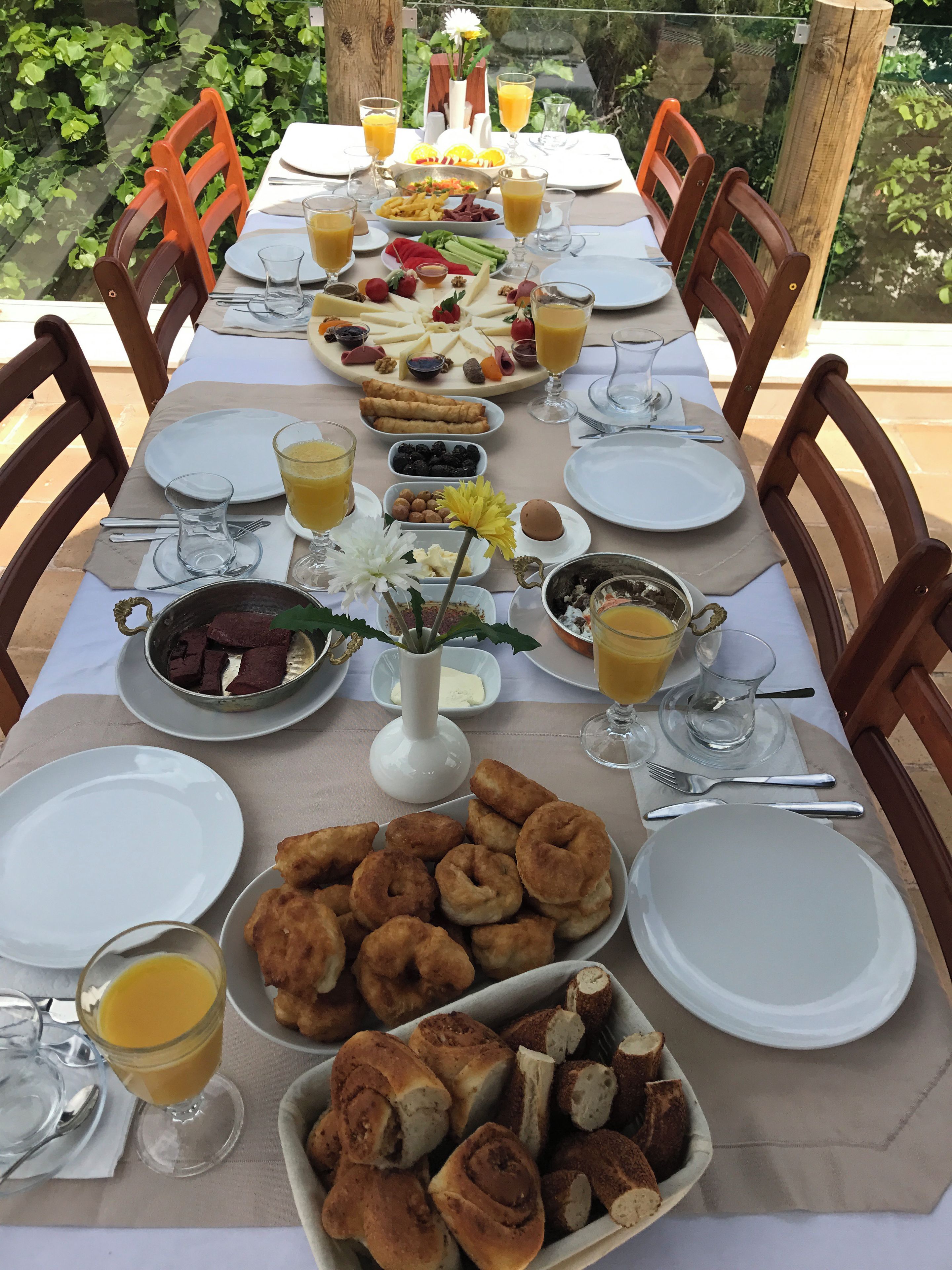 Une table mise pour le petit-déjeuner, avec différents plats, des boissons et un vase rempli de fleurs.