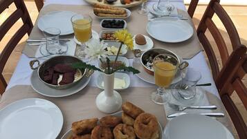 Une table mise pour le petit-déjeuner, avec différents plats, des boissons et un vase rempli de fleurs.