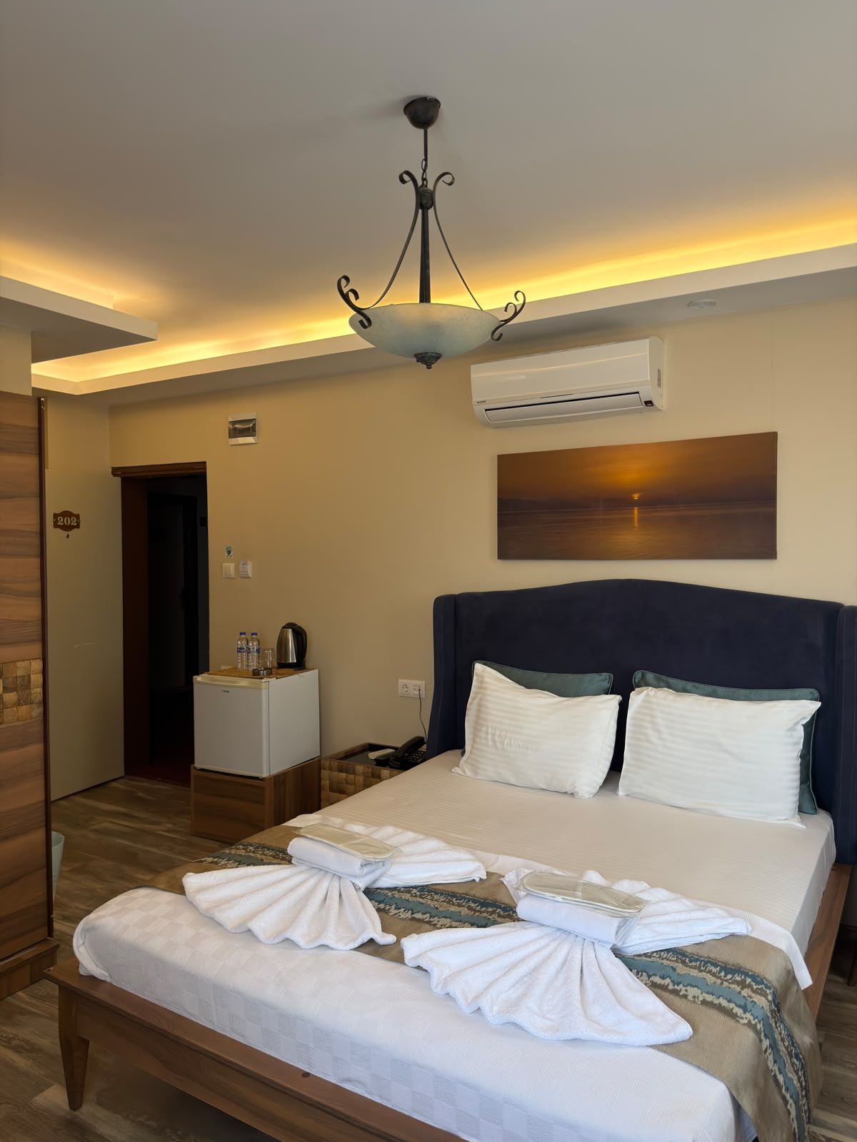 Una habitación de hotel con una cama, una mesita de noche y un aire acondicionado de pared.