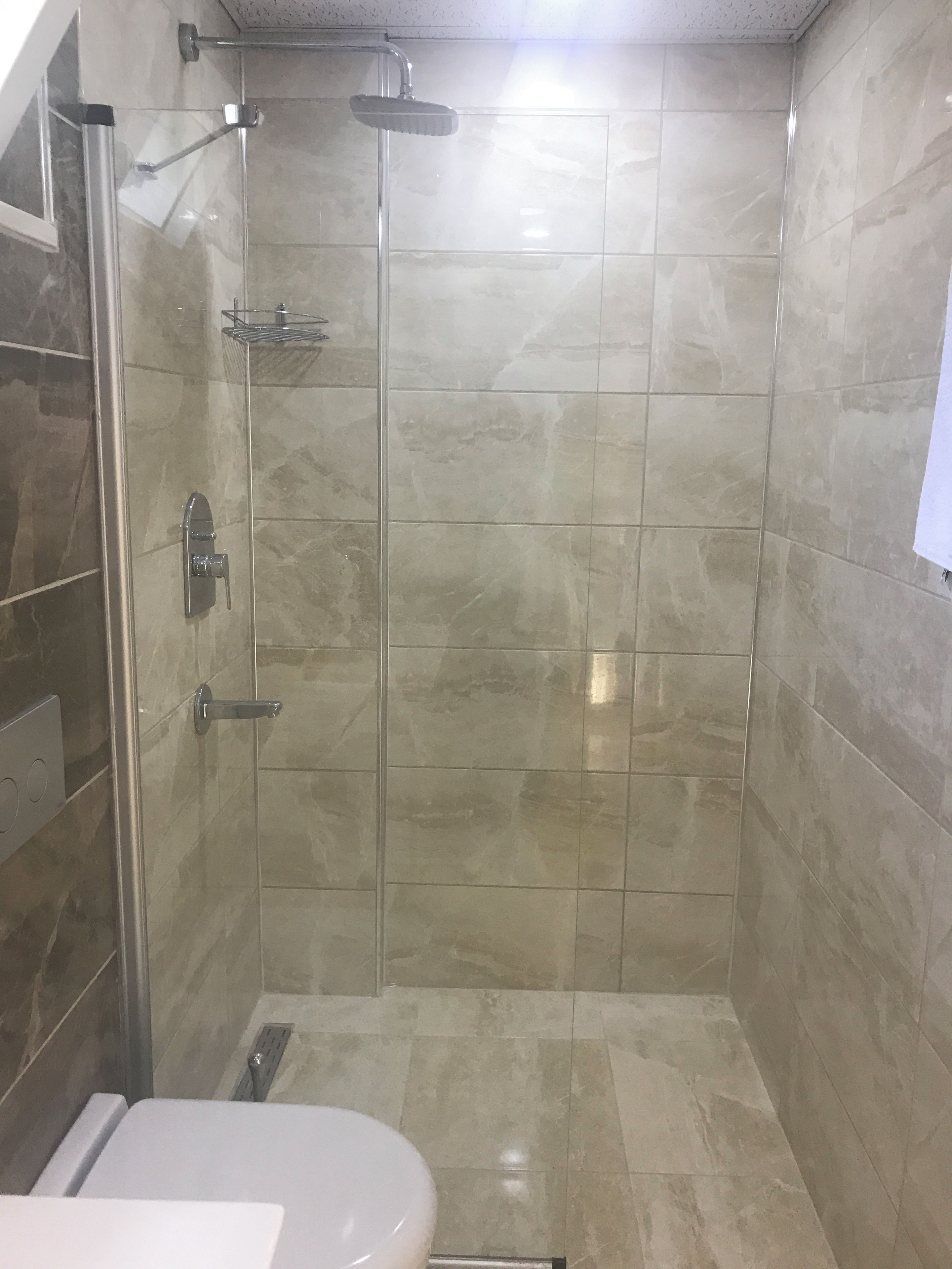 A shower with a glass door, a wall-mounted towel rack, and a showerhead.