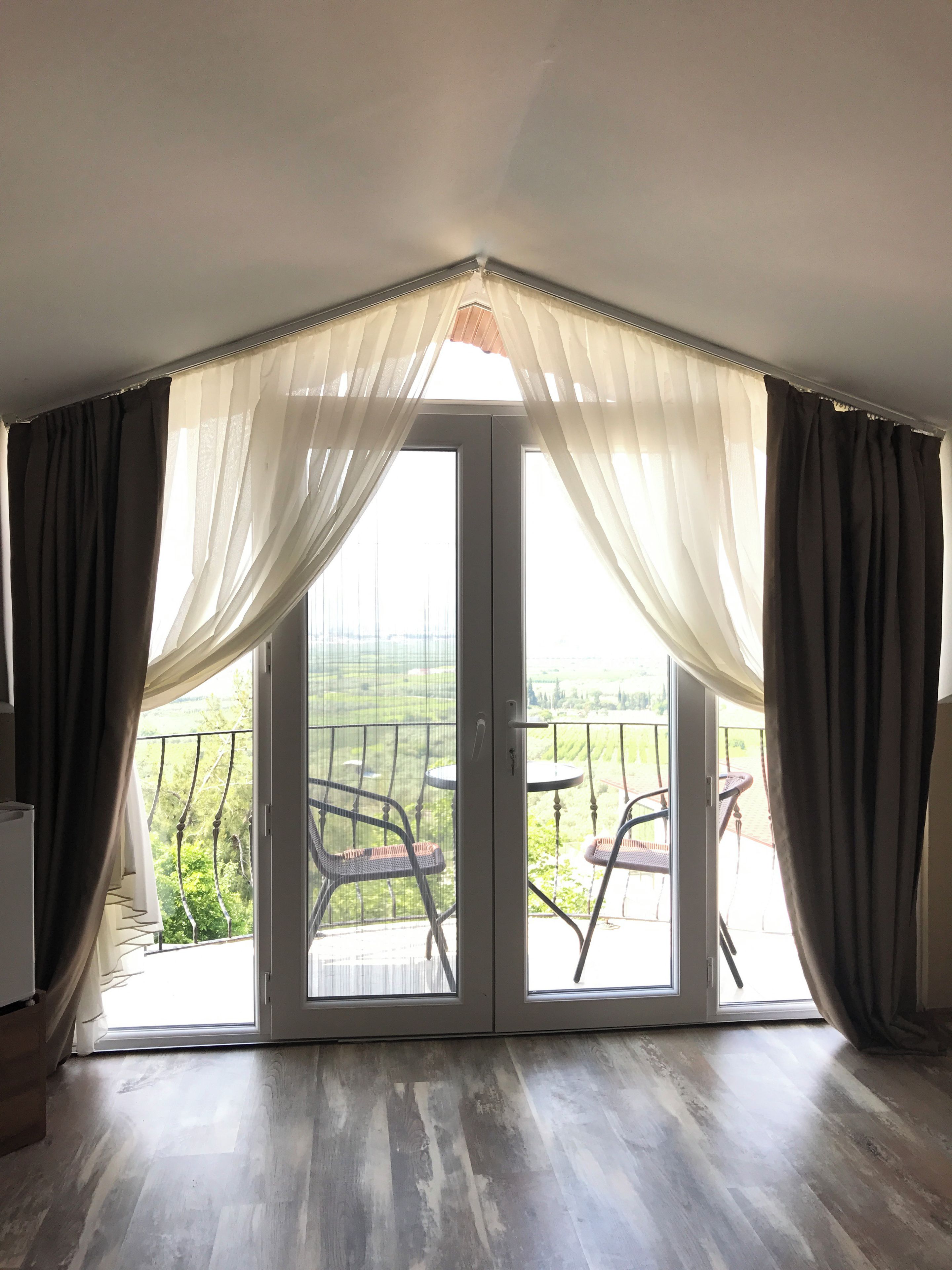 A room with a sliding glass door leading to an outdoor balcony with chairs.