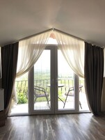 A room with a sliding glass door leading to an outdoor balcony with chairs.