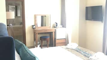 A hotel room with a bed, a desk, a chair, a television, and a bathroom visible through an open door.