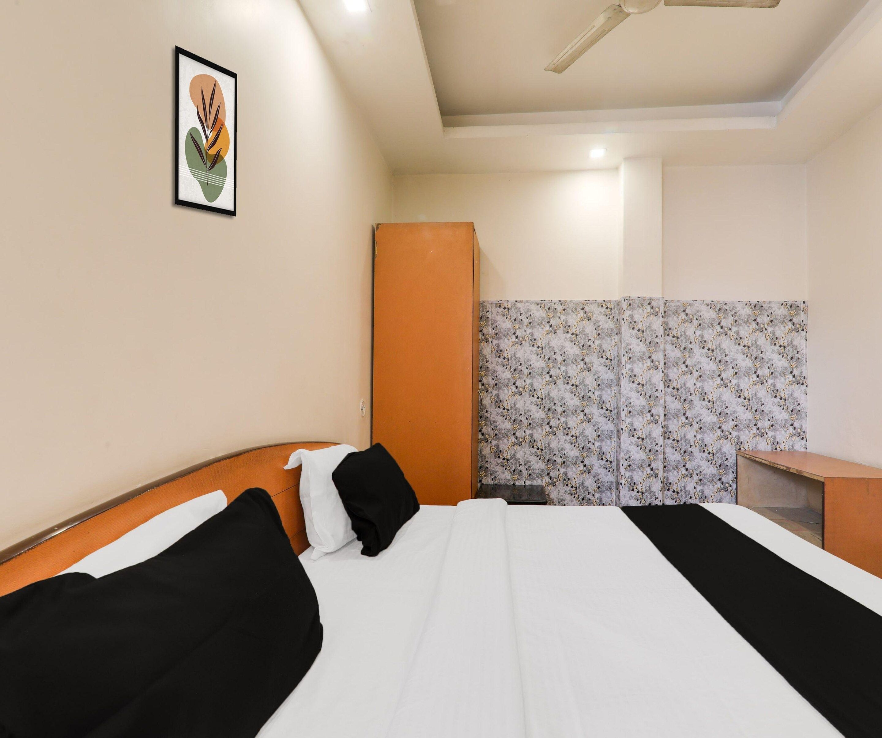 A hotel room with a bed, a wardrobe, a mirror, and a ceiling fan.