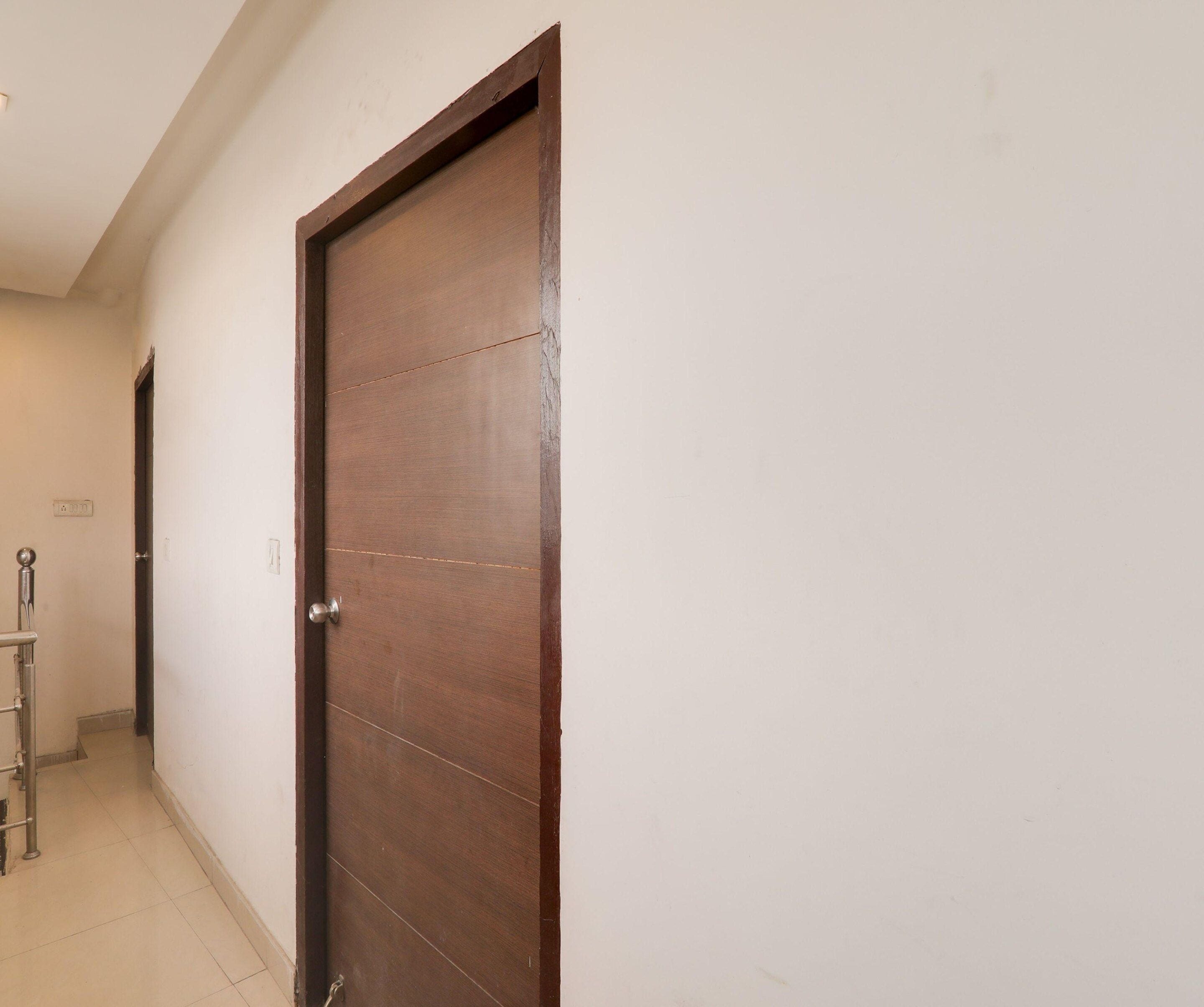 A closed wooden door with a metal handle, a white wall, and a tiled floor.
