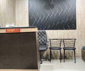 A reception area with a reception desk, two chairs, and a patterned wall. - Classic Tj International (Lucknow)