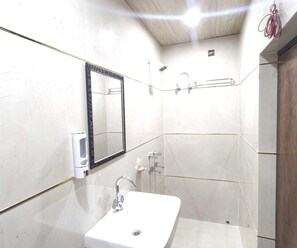 A bathroom with a white sink, a mirror, a shower, and a toilet. - Classic Tj International (Lucknow)