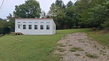 A white building with a red roof, surrounded by a grassy area and trees.