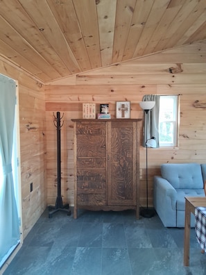 A wooden interior with a cabinet, a coat rack, a lamp, and a sofa.