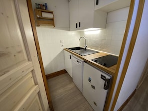 Een kleine keuken met een spoelbak, vaatwasser en een houten aanrecht.