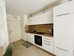 Eine kleine Küche mit weißen Schränken, einer Holz Arbeitsplatte, einem eingebauten Ofen und einem Spülbecken.