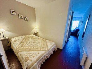 A bedroom with a bed, a nightstand, a lamp, and a wall with two framed pictures. - Bright apartment, AC, view of the pond - 2 guests (Balaruc-les-Bains)