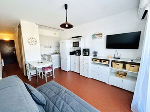 Ein gemütlicher Wohnbereich mit Küchenzeile, Essplatz und einem an der Wand befestigten Fernseher.