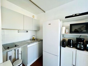 A compact kitchen with a built-in microwave, a sink, and a coffee maker. - Bright apartment, AC, view of the pond - 2 guests (Balaruc-les-Bains)
