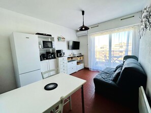 Ein kompakter Wohnbereich mit Küchenzeile, einem Esstisch, einer Couch und einem Fernseher.
