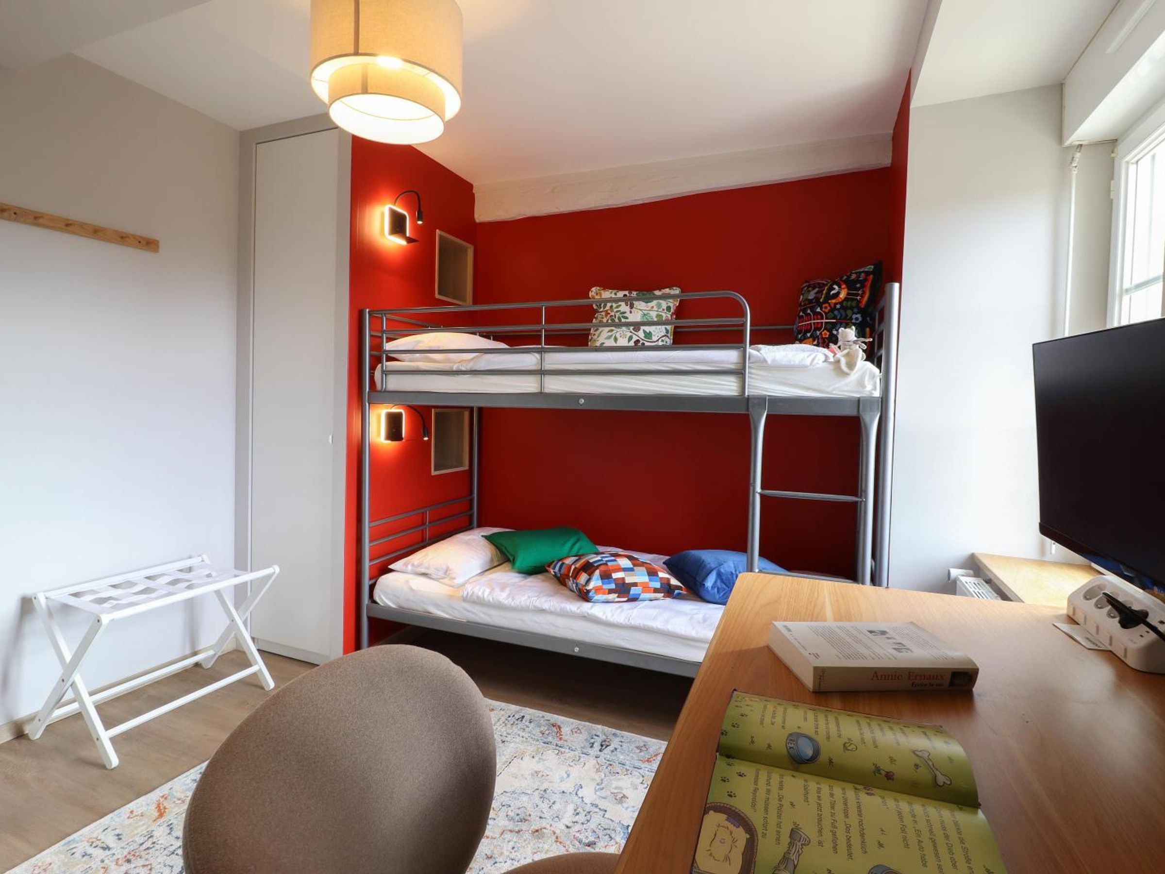 Une chambre avec un lit superposé, une télévision, un bureau et une chaise.