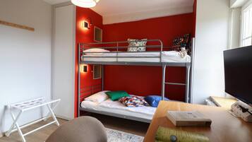 A bunk bed room with a television, a desk, and a chair.