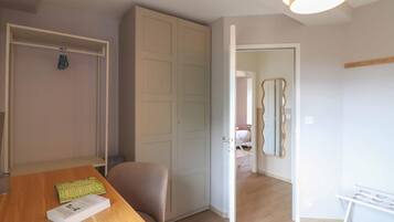 A room with a wooden dining table, a white chair, a wardrobe, and a mirror on the wall.