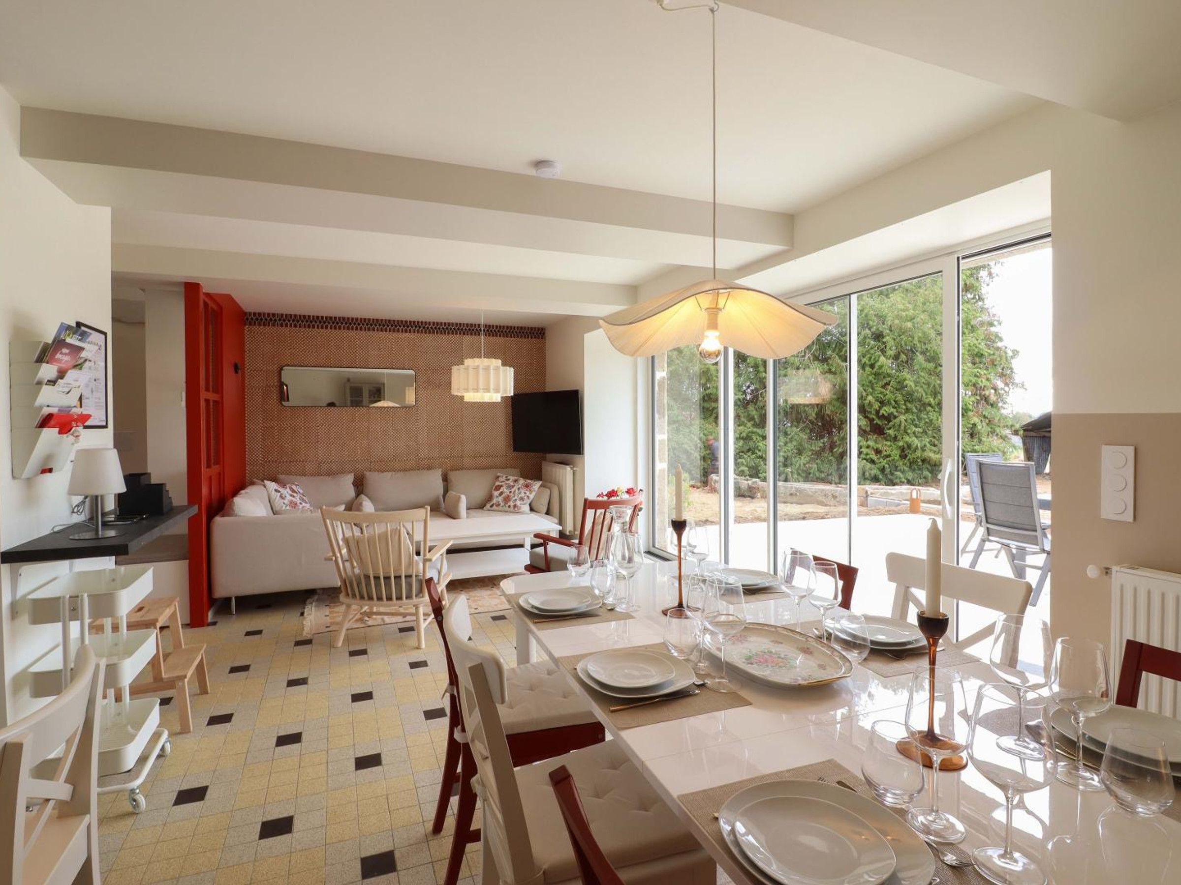 A dining area with a table set for six, a sofa, and a TV mounted on the wall.