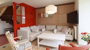 A living room with a sofa set, a coffee table, a TV, and a staircase.