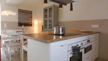 A modern kitchen with white cabinetry, a wooden countertop, and a built-in oven.
