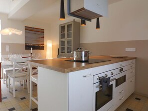 Una cuina moderna amb armaris blancs, un taulell de fusta i forn de sobreencastrat.