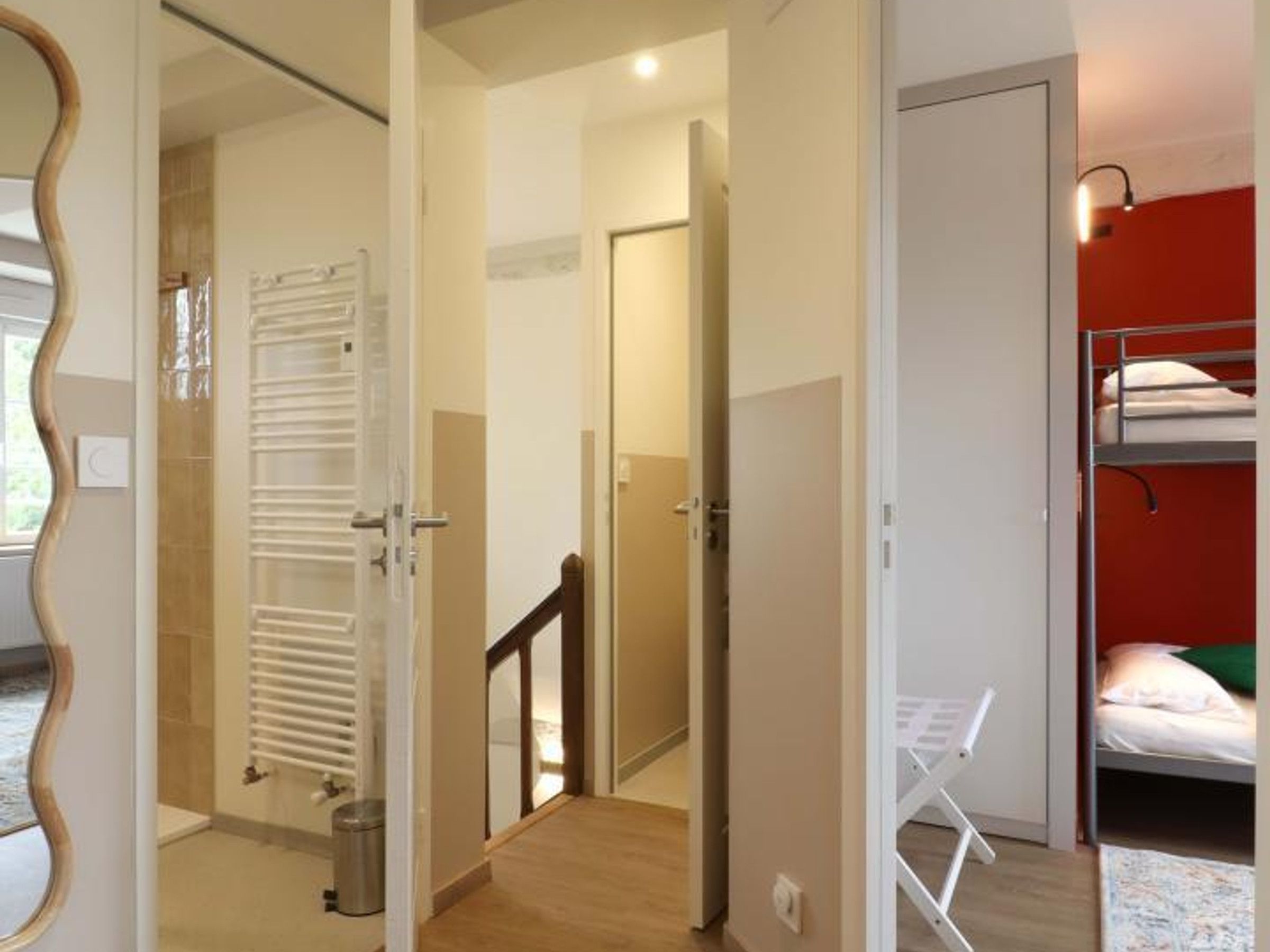Une pièce avec un lit superposé, un radiateur, une porte et un couloir.